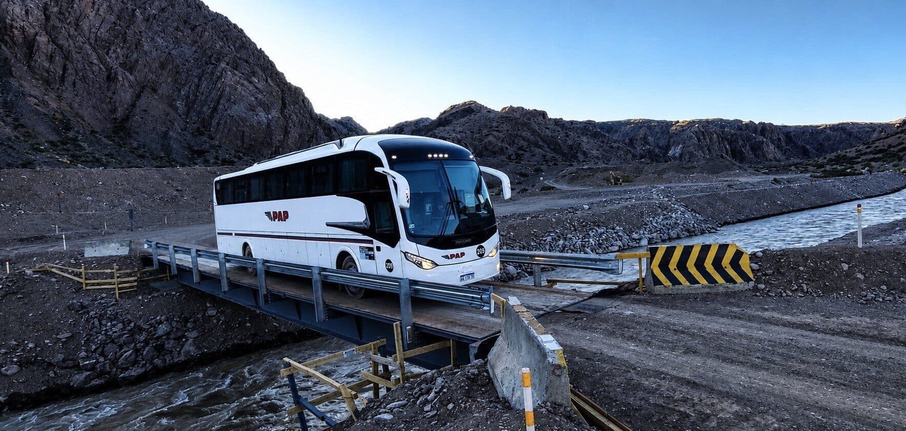 Bus PAP cruzando un puente en un camino de cordillera